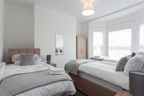 a white bedroom with two beds and a window at Spacious Comfortable house close to Etihad+parking in Manchester
