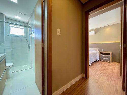 un baño con una puerta de cristal que conduce a un dormitorio en Apartamento 2 dorm e VARANDA a 3 QD RUA COBERTA, en Canela