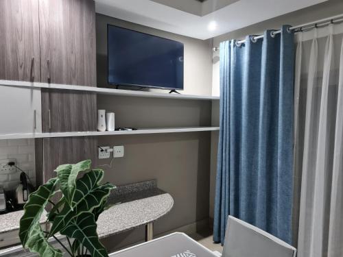 ein Wohnzimmer mit einem TV und einem Stuhl in der Unterkunft Stunning City Living at Loftus in Pretoria
