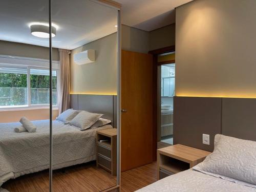 1 dormitorio con 2 camas y espejo en Apartamento 2 dorm e VARANDA a 3 QD RUA COBERTA, en Canela