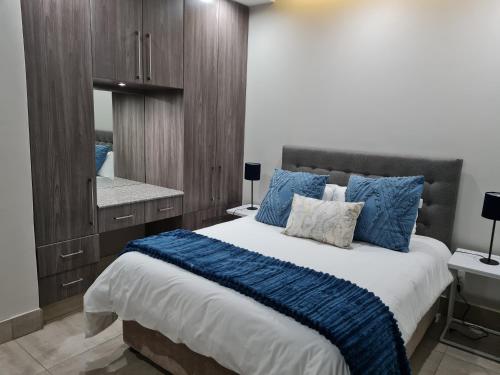 a bedroom with a large bed with blue pillows at Stunning City Living at Loftus in Pretoria