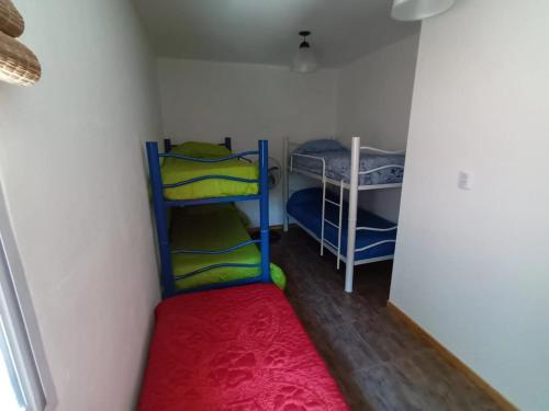 Habitación pequeña con 2 literas y alfombra roja. en Casa Los Duraznos en San Rafael