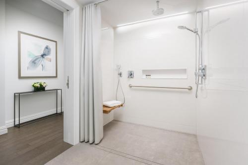 La salle de bains est pourvue de murs blancs et d'une cabine de douche. dans l'établissement The Wallace Hotel, à New York