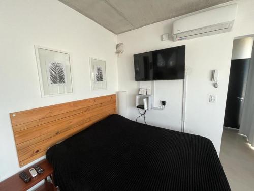 a bedroom with a bed and a tv on the wall at Luminoso Depto 40 metros NUEVO. Excelente Ubicacion Zona Sur. in Remedios de Escalada