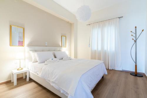 a white bedroom with a white bed and a window at Boutique Apartment with ParkView in Heraklio Town