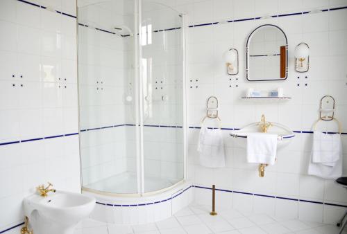 a white bathroom with a shower and a sink at Hotel Alt-Karow in Berlin