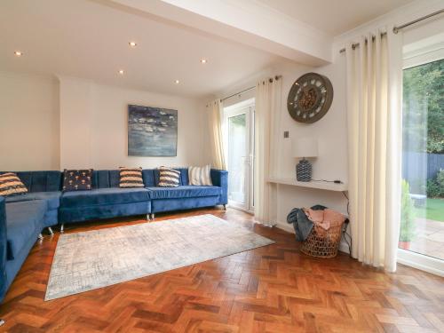 a living room with a blue couch and a wooden floor at 4 Woodland Park in Bideford