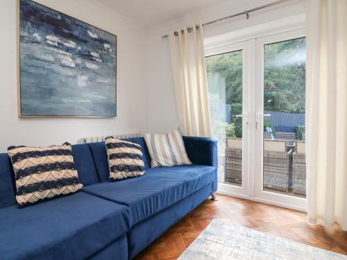 a blue couch in a living room with a sliding glass door at 4 Woodland Park in Bideford