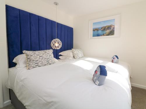 a bedroom with two white beds and a blue headboard at 4 Woodland Park in Bideford