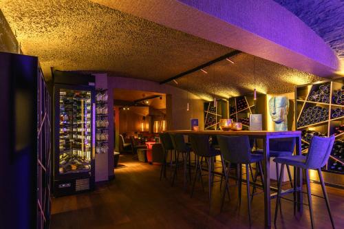 a bar in a wine cellar with purple bar stools at Hotel Erasmus - Mein Genuss- und Wellnesshotel in Trassem