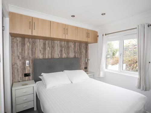 a bedroom with a white bed and a window at The Warren U5 in Abersoch