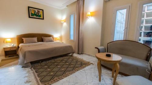 a bedroom with a bed and a couch and a table at HOTEL LAFAYETTE in Tunis