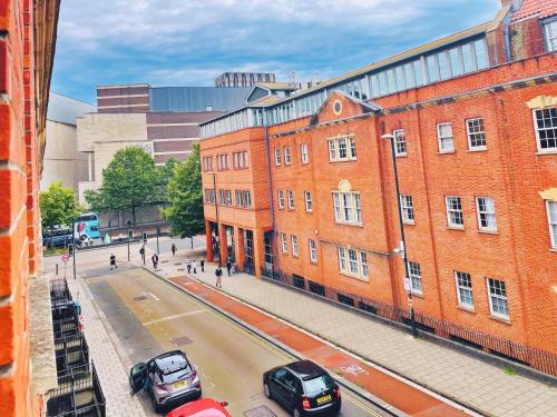 a street with cars parked in front of a brick building at Bristol City Stays - Cabot Circus in Bristol
