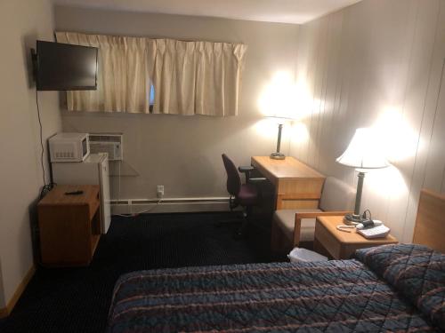a hotel room with a bedroom with a bed and a desk at Parkway Motel in Neenah