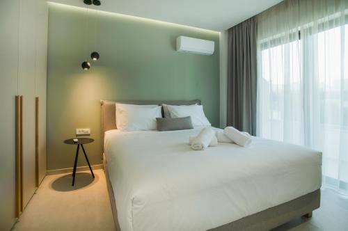 una camera da letto con un grande letto bianco e una finestra di Celine Luxury Apartments & Suites ad Ágios Nikólaos