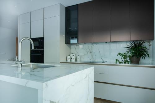 una cucina bianca con lavandino e armadi neri di Celine Luxury Apartments & Suites ad Ágios Nikólaos