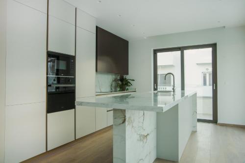 a kitchen with white cabinets and a marble counter top at Celine Luxury Apartments & Suites in Agios Nikolaos