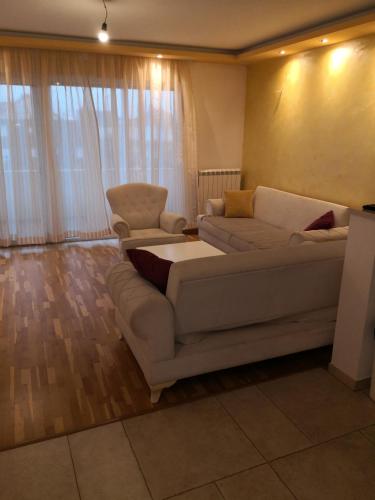 een woonkamer met een bank en 2 stoelen bij 3 A LUX Apartmani in Podgorica