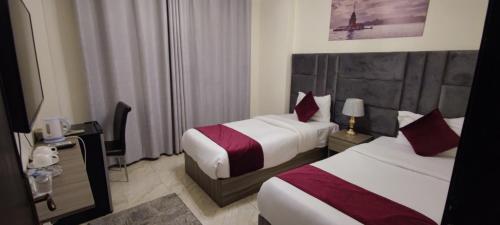 a hotel room with two beds and a television at Golden Hotel in Amman