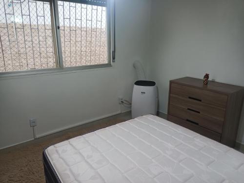 a bedroom with a bed and a dresser and a window at Apto em Santa Maria in Santa Maria