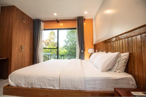 a bedroom with a large white bed with a window at Siem Reap Homesteading in Siem Reap