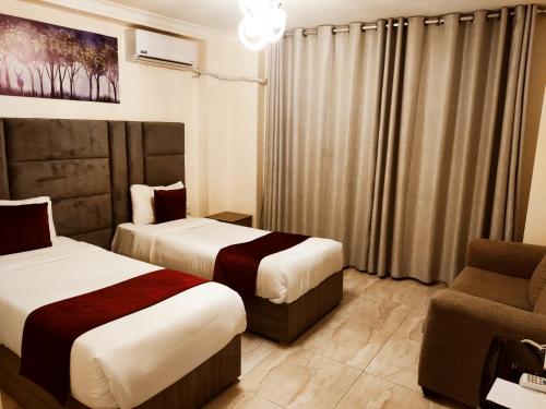 a hotel room with two beds and a chair at Golden Hotel in Amman