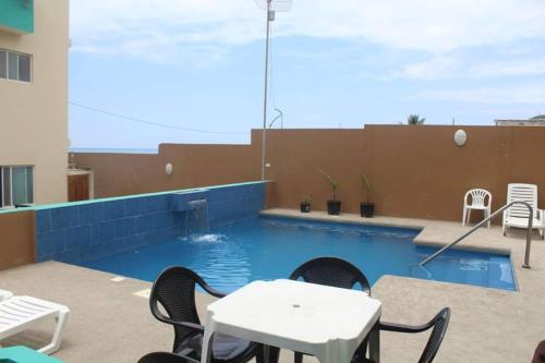 a patio with a table and chairs and a pool at The Lookout Beach Hotel in San Lorenzo