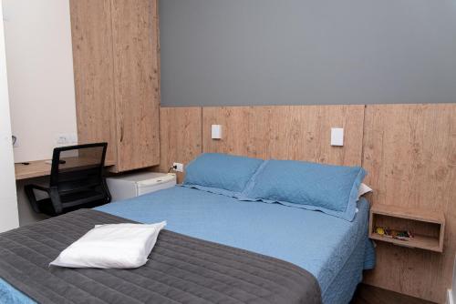 1 dormitorio con cama azul y silla negra en Hotel Descalvado, en Descalvado