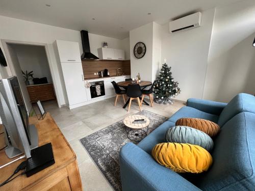 un salon avec un canapé bleu et un arbre de Noël dans l'établissement Appartement plain-pied au coeur de l'Alsace, à Muttersholtz