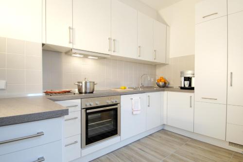 Biała kuchnia z białymi szafkami i urządzeniami w obiekcie Apartement in Stadtvilla w Berlinie