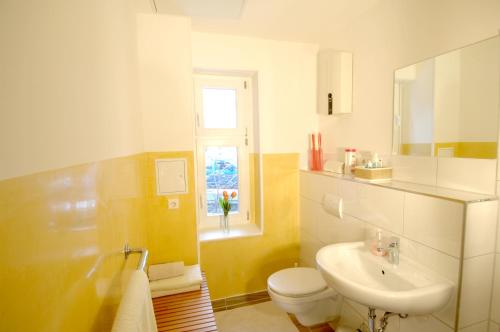 ein Bad mit einem Waschbecken, einem WC und einem Fenster in der Unterkunft Apartement in Stadtvilla in Berlin