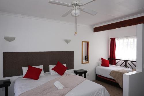 ein Schlafzimmer mit zwei Betten mit roten Kissen in der Unterkunft Sheba Rock Guesthouse in Nelspruit