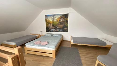 Cette chambre comprend deux lits et un tableau mural. dans l'établissement Apartamenty Młynne, à Muszyna