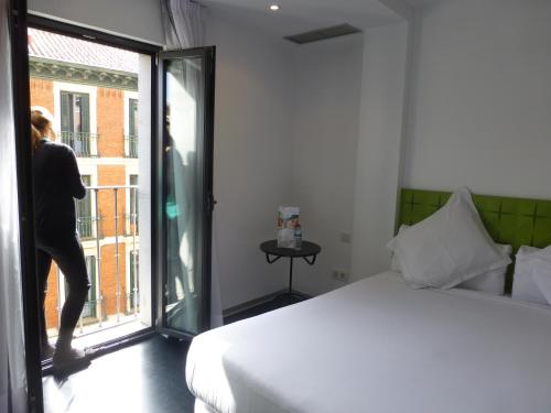 a person is looking out the window of a bedroom at Mayerling Hotel in Madrid