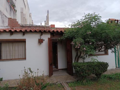 a white house with a door and a tree at La Cara Oculta de Salta, bed and breakfast in Salta