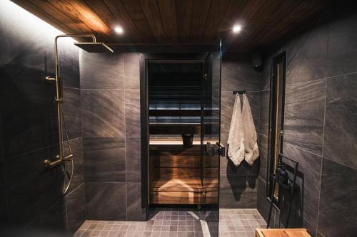 Un baño con ducha con puerta de cristal. en Le-Villa Black, en Levi