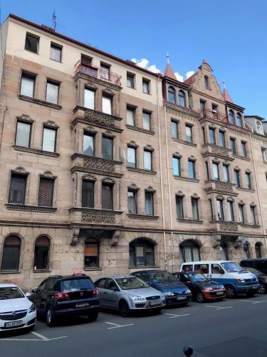 a large building with cars parked in front of it at Lovely Apartment close to the Heart of Nürnberg in Nürnberg