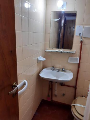 un bagno con lavandino, specchio e WC di Hostería Vecchia Costa a San Bernardo
