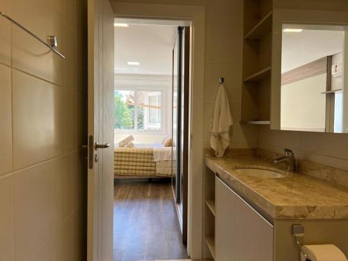 a bathroom with a sink and a bathroom with a bed at Apartamentos Altos da Bela Vista by Achei Gramado in Gramado