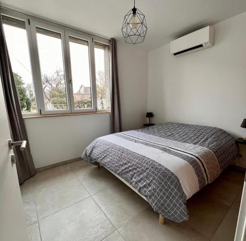 - une chambre avec un lit et 2 fenêtres dans l'établissement Appartement plain-pied au coeur de l'Alsace, à Muttersholtz