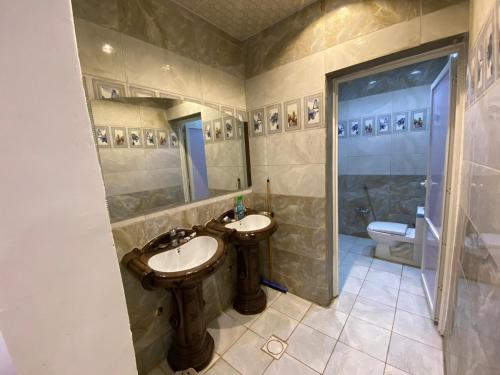 a bathroom with two sinks and a shower and a toilet at Almazham holiday house in AlUla