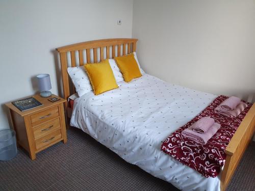 um quarto com uma cama com almofadas amarelas e uma mesa de cabeceira em Alastrean Flat em Aberdeen