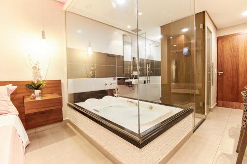 uma casa de banho com uma banheira e uma parede de vidro em Intense Motel em São Paulo