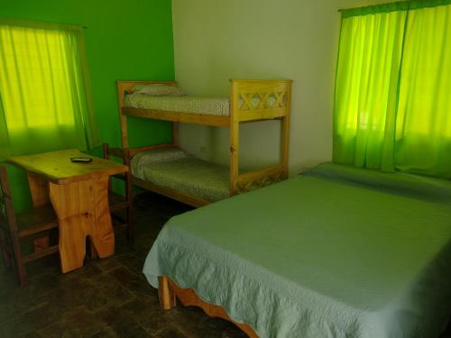 ポトレロ・デ・ロス・フネスにあるCabañas El Doralの緑の壁のベッドルーム(ベッド1台、テーブル付)
