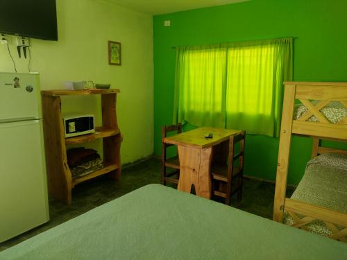 a green room with a bed and a table and a refrigerator at Cabañas El Doral in Potrero de los Funes