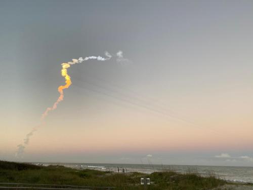 a trail of smoke in the sky over the ocean at Surf Studio Beach Resort in Cocoa Beach