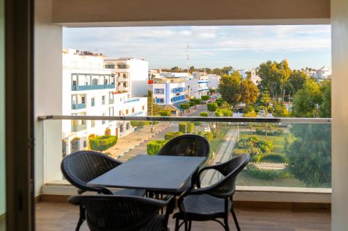 a balcony with a table and chairs and a large window at PUERTO MARINA ASILAH in Asilah