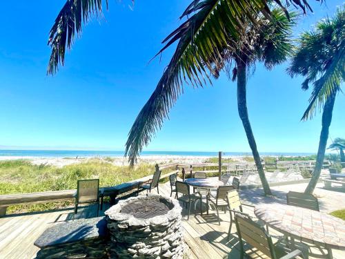 a table and chairs on the beach with palm trees at Surf Studio Beach Resort in Cocoa Beach