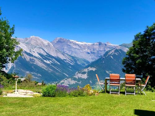 two chairs sitting on a lawn with mountains in the background at Magnifique Maison près du centre in Nendaz