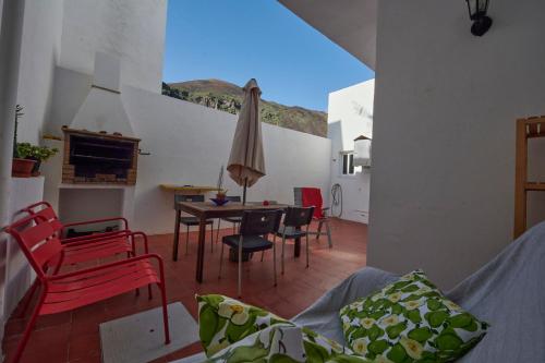 ein Wohnzimmer mit einem Tisch, Stühlen und einem Sonnenschirm in der Unterkunft Mar y Sol Casa Con Terraza y Barbacoa A 10 Metros del Mar in Tamaduste